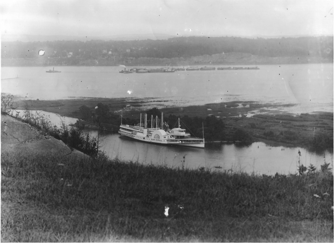 Black and white photograph of the steamboat Mary Powell at Sunflower Dock on Rondout Creek, tugboat with tow on the Hudson River in the background.